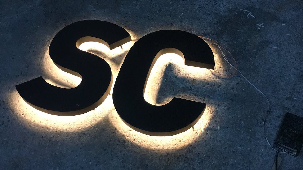 creative-01 LED backlit 'SC' letters on concrete surface, creating a glowing effect.